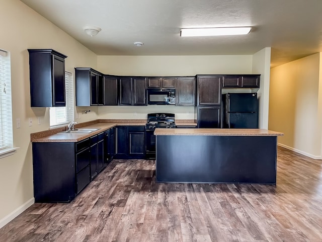 kitchen featuring sink, a kitchen island, black appliances, and hardwood / wood-style flooring