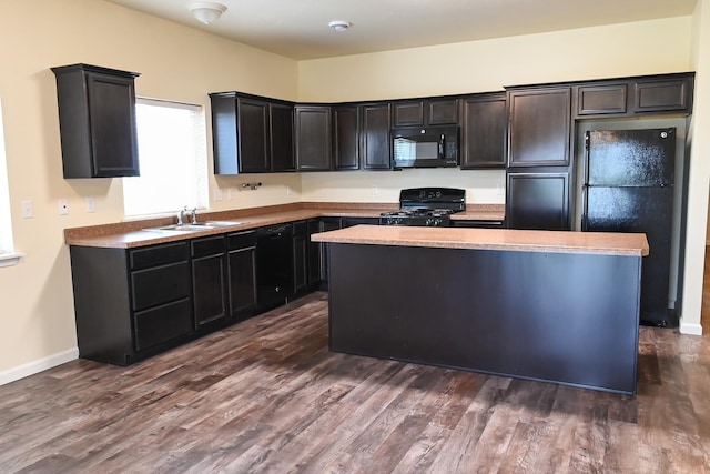 kitchen with sink, dark hardwood / wood-style floors, a kitchen island, and black appliances