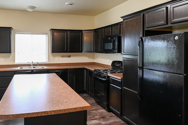 kitchen with dark wood-type flooring, a center island, black appliances, and sink