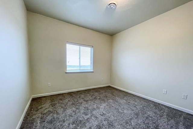 unfurnished room featuring dark colored carpet