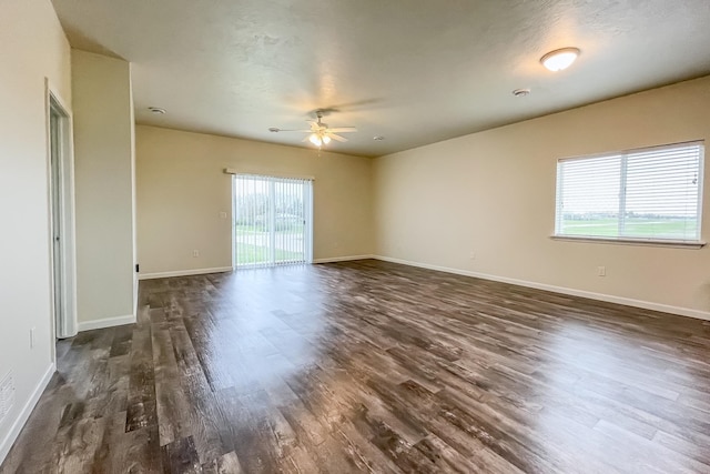 spare room featuring ceiling fan, plenty of natural light, and dark wood-type flooring