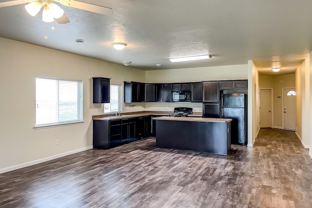 kitchen featuring sink, a center island, dark hardwood / wood-style flooring, a textured ceiling, and black appliances