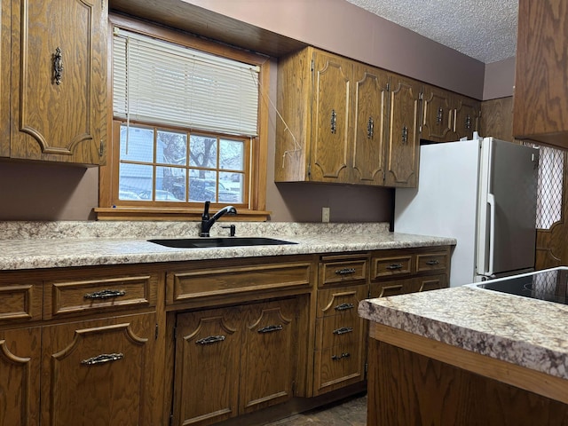 1107 SE 2nd St, Minot, ND 58701 - kitchen with freestanding refrigerator, a sink, light countertops, and a textured ceiling