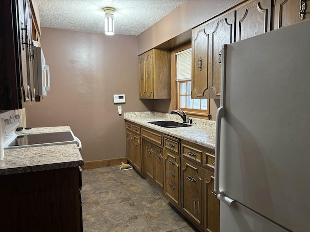 1107 SE 2nd St, Minot, ND 58701 - kitchen with white appliances, a sink, baseboards, a textured ceiling, and light countertops