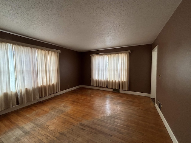 1107 SE 2nd St, Minot, ND 58701 - unfurnished room with wood finished floors, a textured ceiling, and baseboards