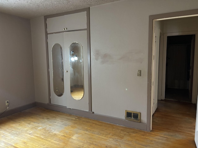 1107 SE 2nd St, Minot, ND 58701 - spare room featuring light wood-type flooring, a textured ceiling, and baseboards