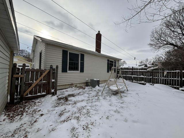 1107 SE 2nd St, Minot, ND 58701 - view of snowy exterior featuring central air condition unit, a chimney, and a gate