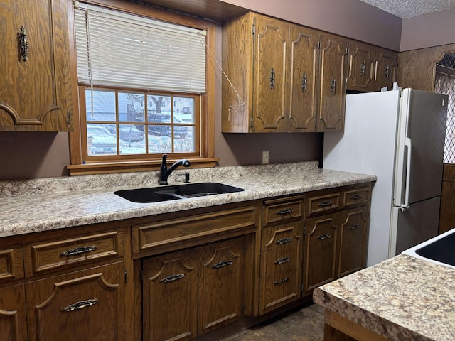 1107 SE 2nd St, Minot, ND 58701 - kitchen with freestanding refrigerator, a sink, light countertops, and a textured ceiling