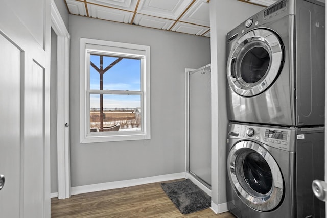 clothes washing area featuring dark hardwood / wood-style floors and stacked washer / drying machine