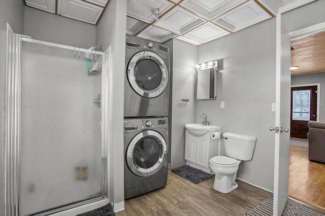 bathroom featuring vanity, coffered ceiling, hardwood / wood-style flooring, walk in shower, and stacked washer / dryer