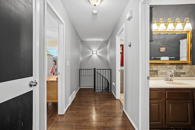 hallway with a textured ceiling, dark hardwood / wood-style flooring, and sink