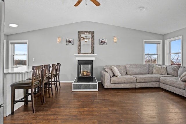 living room featuring dark hardwood / wood-style floors, vaulted ceiling, and ceiling fan