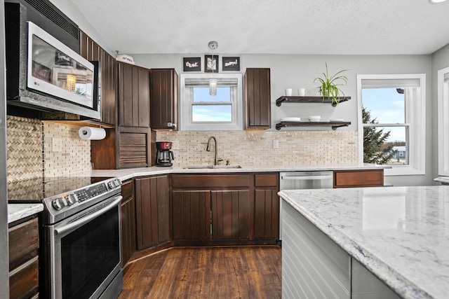 kitchen with light stone countertops, appliances with stainless steel finishes, dark hardwood / wood-style flooring, dark brown cabinets, and sink