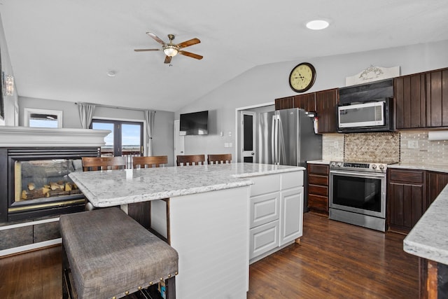 kitchen featuring a kitchen breakfast bar, dark hardwood / wood-style floors, a kitchen island, dark brown cabinetry, and stainless steel appliances