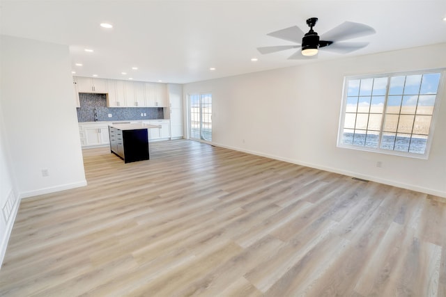 3308 23rd Ave NW, Minot, ND 58703 - unfurnished living room featuring ceiling fan, a healthy amount of sunlight, light hardwood / wood-style floors, and sink