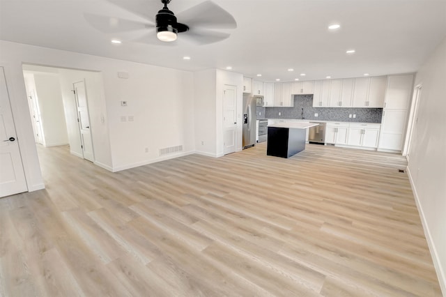3308 23rd Ave NW, Minot, ND 58703 - kitchen with white cabinets, a kitchen island, light wood-type flooring, and stainless steel appliances