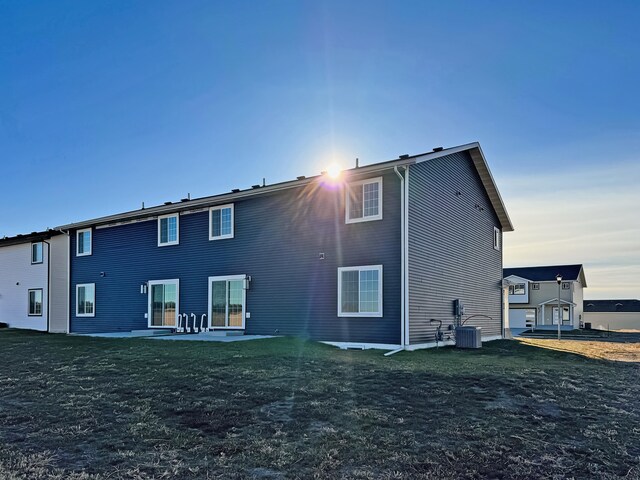 3308 23rd Ave NW, Minot, ND 58703 - back of property with a lawn, cooling unit, and a patio area
