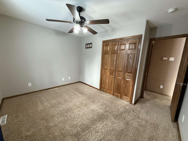 unfurnished bedroom featuring ceiling fan, light colored carpet, and a closet