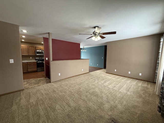 unfurnished living room featuring ceiling fan with notable chandelier and dark carpet