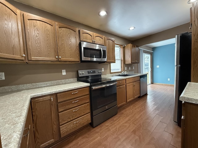 kitchen with stainless steel appliances, light hardwood / wood-style floors, and sink