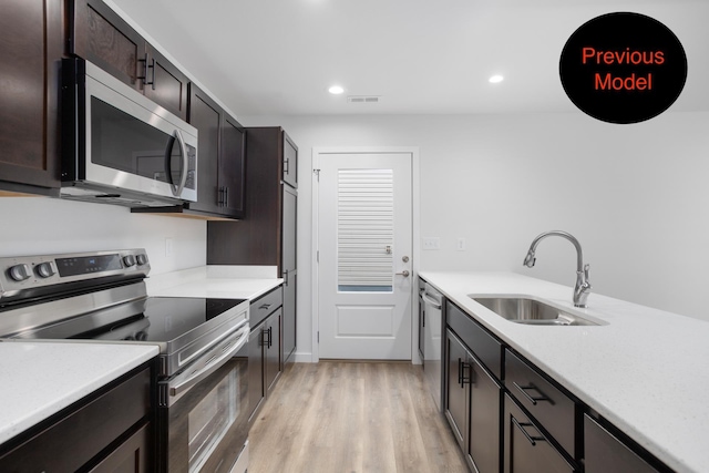 kitchen with dark brown cabinetry, sink, light wood-type flooring, and appliances with stainless steel finishes