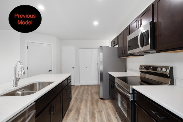 kitchen with dark brown cabinets, sink, appliances with stainless steel finishes, and light hardwood / wood-style flooring