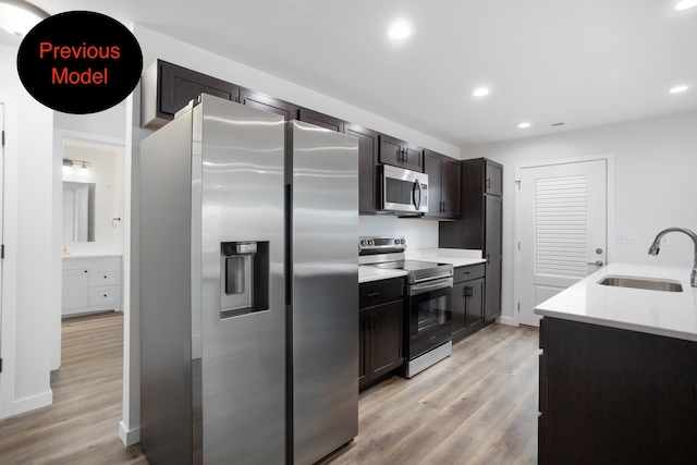 kitchen with dark brown cabinets, sink, stainless steel appliances, and light hardwood / wood-style flooring