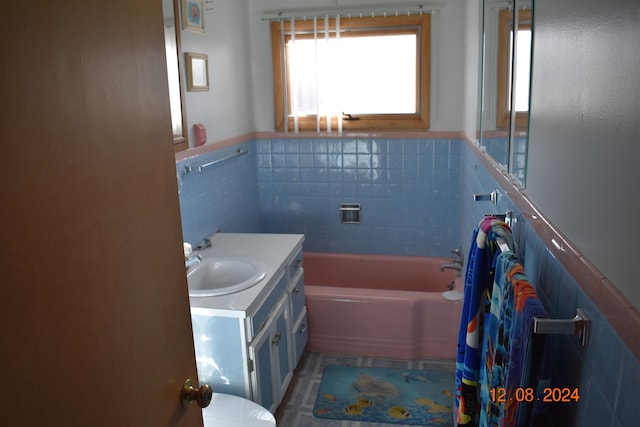 bathroom featuring tile patterned flooring, vanity, tile walls, and a tub