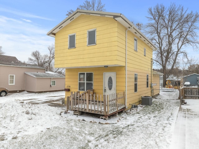 snow covered house with a deck and cooling unit