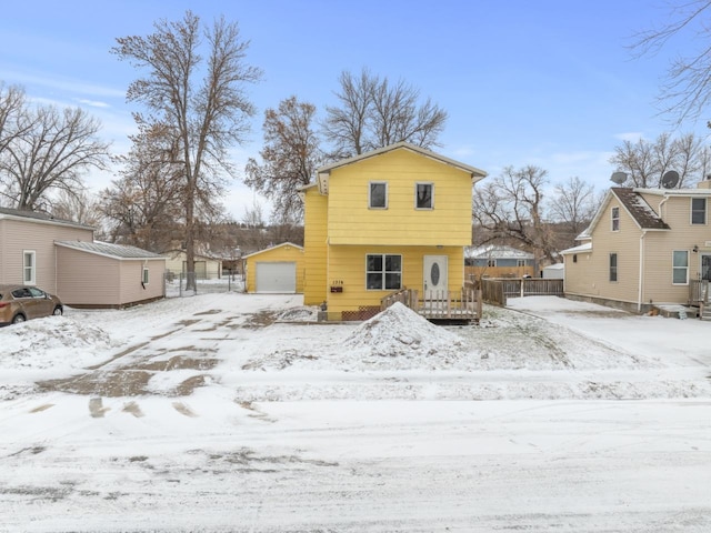 snow covered rear of property featuring an outdoor structure and a garage