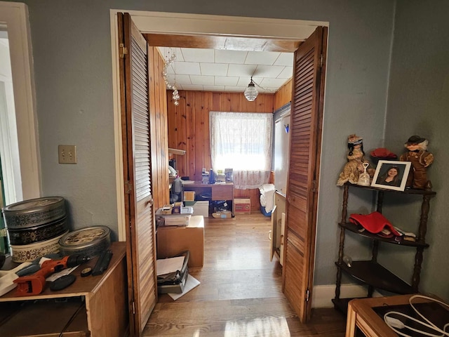 corridor with wood walls and light hardwood / wood-style floors