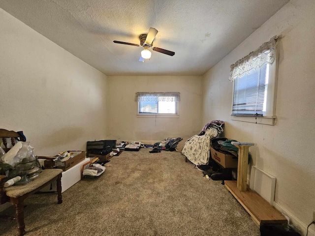 sitting room featuring ceiling fan, carpet floors, and a textured ceiling