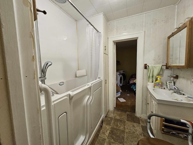 bathroom with vanity, shower / bath combination with curtain, tile walls, and washing machine and clothes dryer