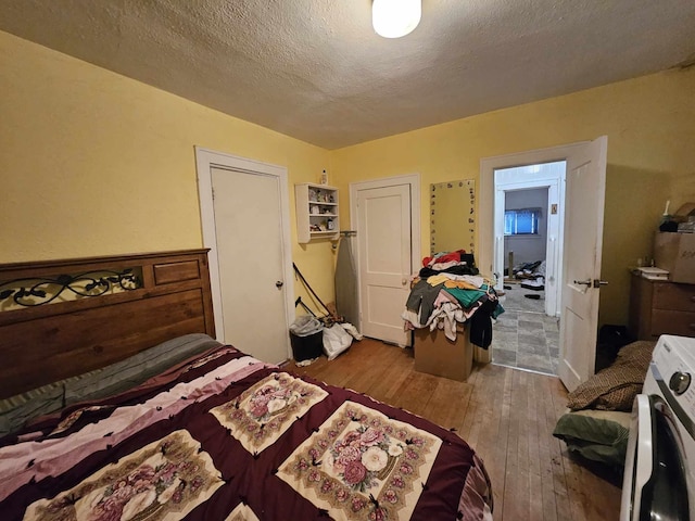 bedroom with washer / clothes dryer, hardwood / wood-style floors, and a textured ceiling