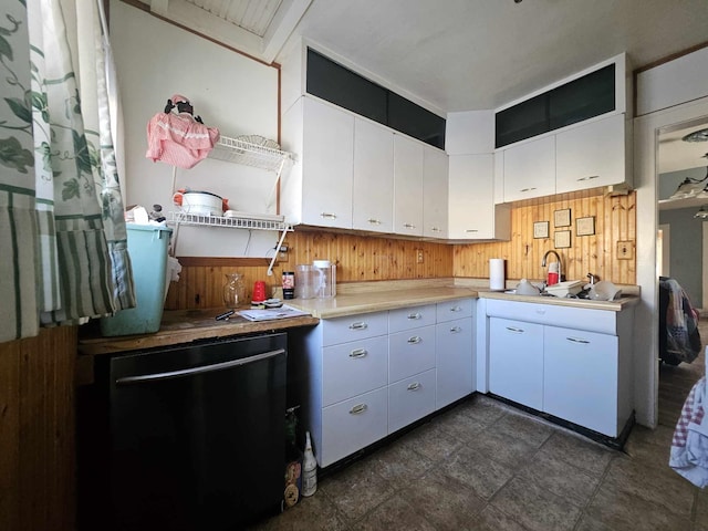 kitchen with white cabinetry, wooden walls, and sink