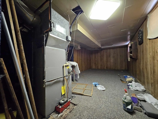 basement with carpet, heating unit, and wood walls