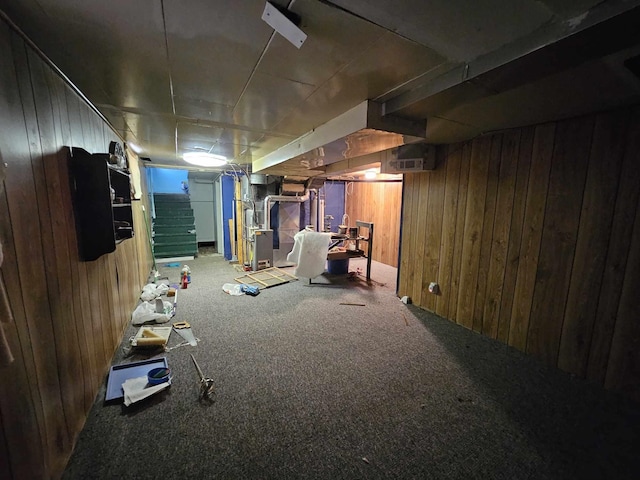 basement featuring carpet floors, heating unit, and wooden walls