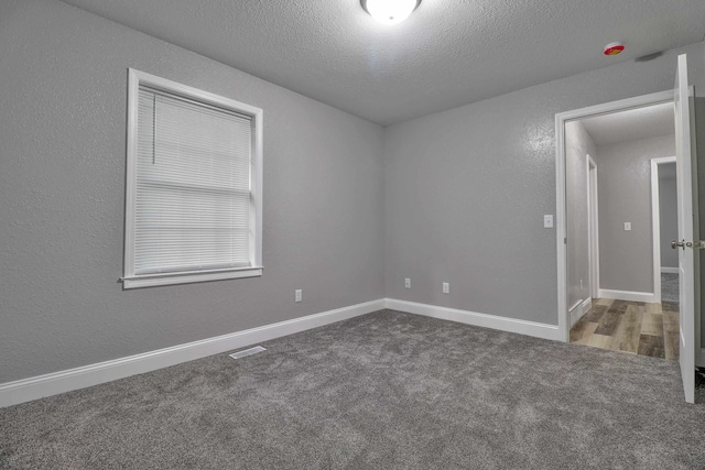 carpeted empty room featuring a textured ceiling