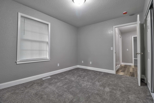 carpeted empty room with a textured ceiling