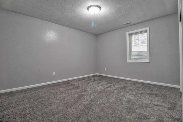 spare room with dark carpet and a textured ceiling