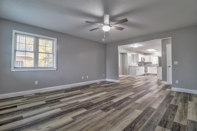 unfurnished living room featuring ceiling fan, dark hardwood / wood-style flooring, and a textured ceiling