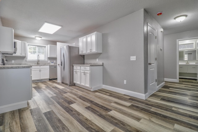 kitchen featuring sink, dark hardwood / wood-style floors, a textured ceiling, appliances with stainless steel finishes, and white cabinetry