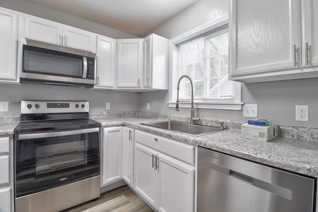 kitchen with white cabinets, light wood-type flooring, sink, and appliances with stainless steel finishes