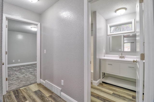 bathroom with hardwood / wood-style floors, vanity, and a textured ceiling