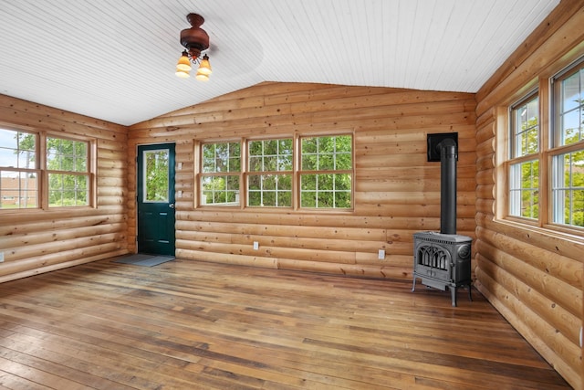 unfurnished living room featuring log walls, hardwood / wood-style floors, a wood stove, and lofted ceiling