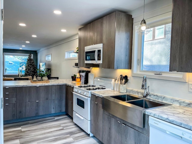 kitchen with a healthy amount of sunlight, light hardwood / wood-style flooring, pendant lighting, and white appliances