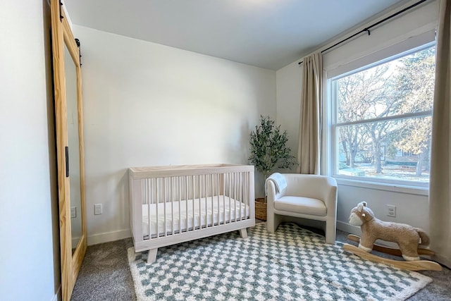 carpeted bedroom featuring a barn door and a crib