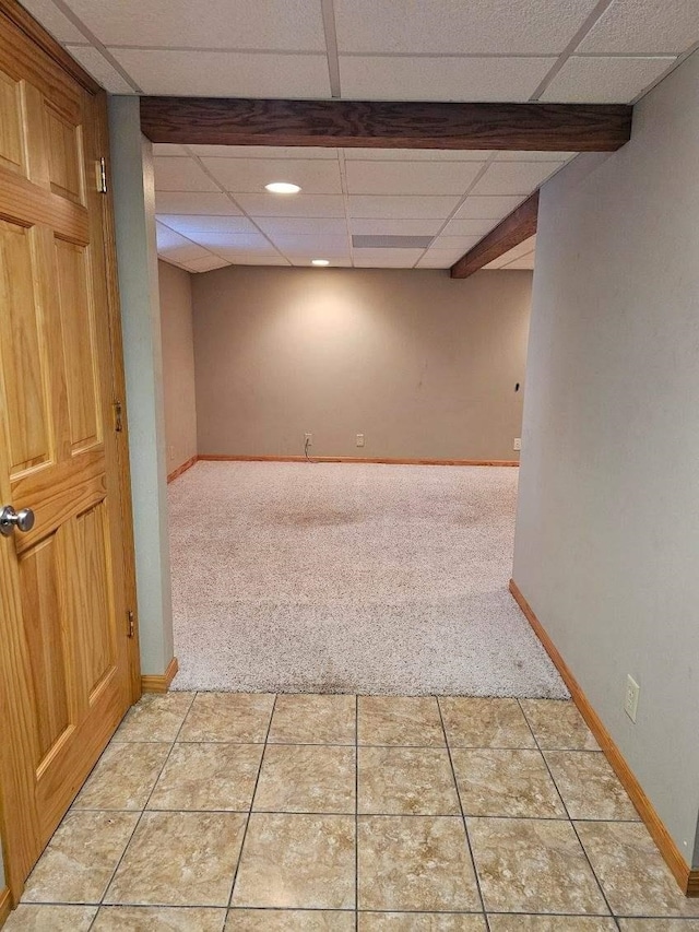 basement featuring a drop ceiling and light tile patterned floors