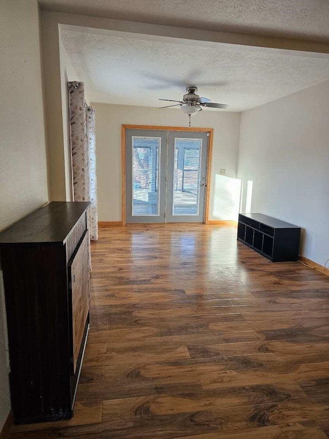 unfurnished living room featuring ceiling fan, dark hardwood / wood-style flooring, and a textured ceiling