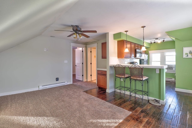 kitchen with ceiling fan, baseboard heating, dark hardwood / wood-style flooring, kitchen peninsula, and a breakfast bar area